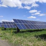 Fileiras de painéis solares em um campo sob céu azul, em Uberlândia, Minas Gerais.