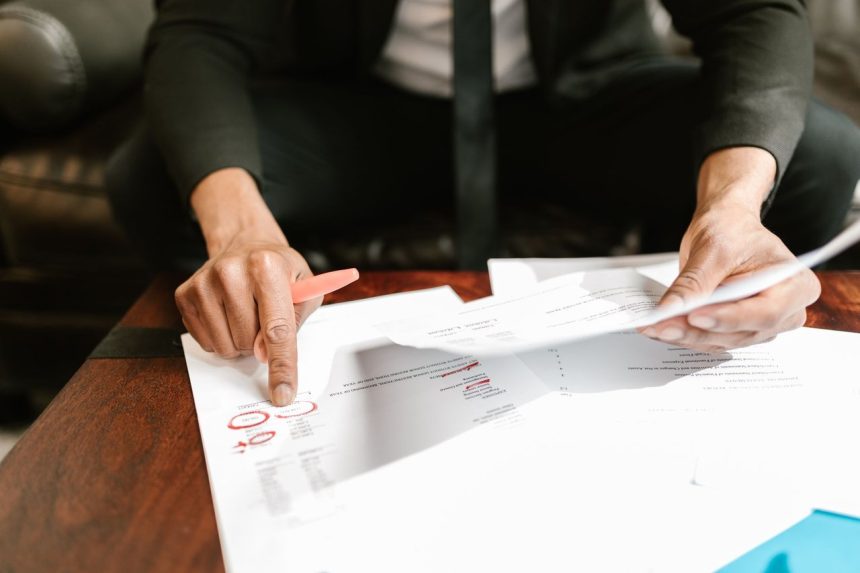 Empresário analisa documentos financeiros e números sobre a mesa em um ambiente de escritório.