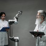 Dois pesquisadores analisam um braço robótico em um laboratório de inovação tecnológica.