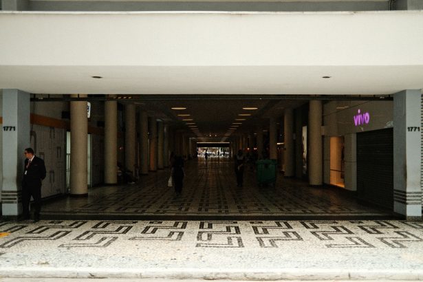 Corredor amplo de um shopping center moderno, com pessoas caminhando entre as lojas.